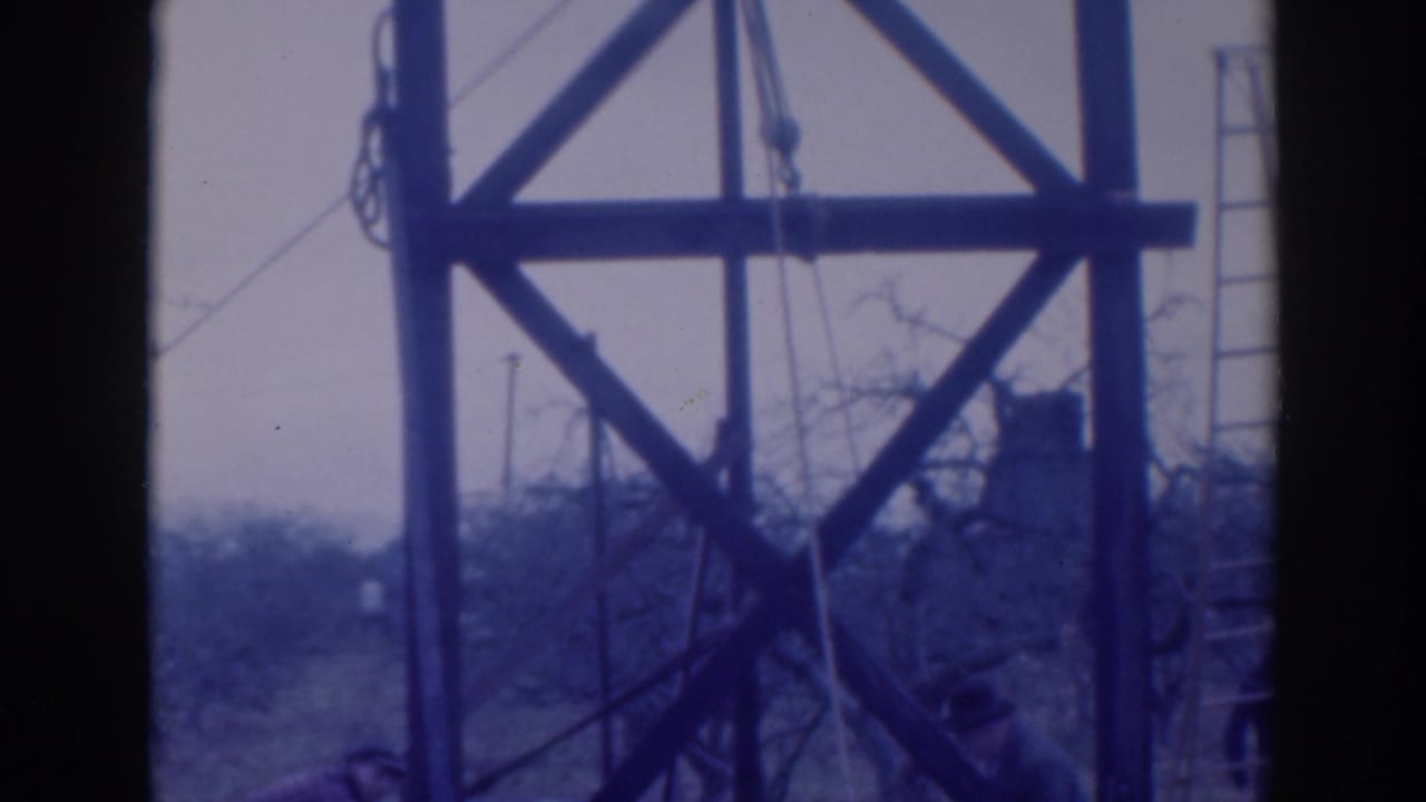 1937 Sacramento 8mm frame showing a wooden utility-like tower with cross-bracing, rope lines, and a ladder near bare branches.