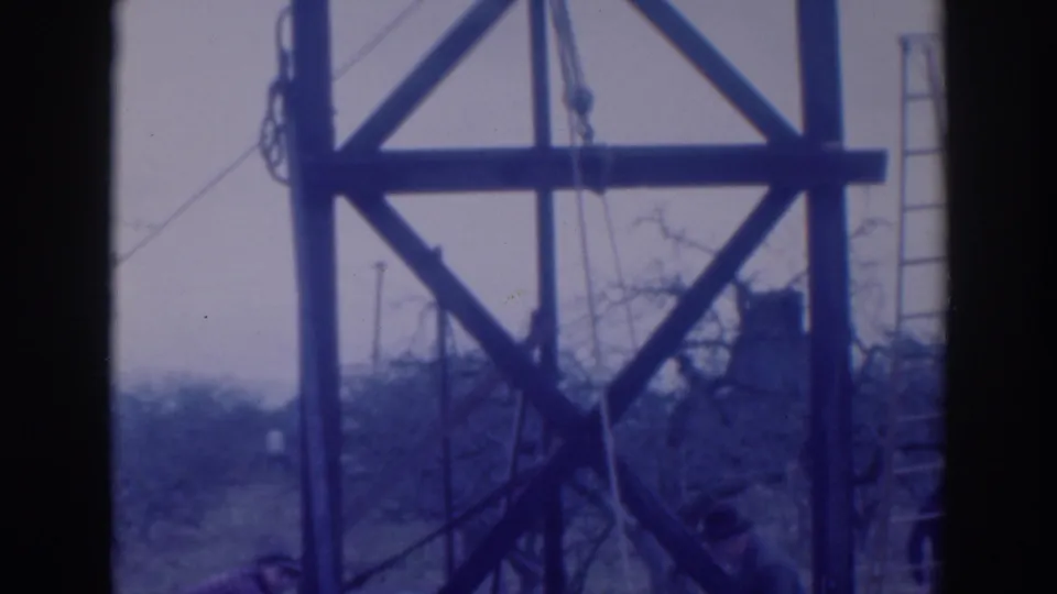 1937 Sacramento 8mm frame showing a wooden utility-like tower with cross-bracing, rope lines, and a ladder near bare branches.