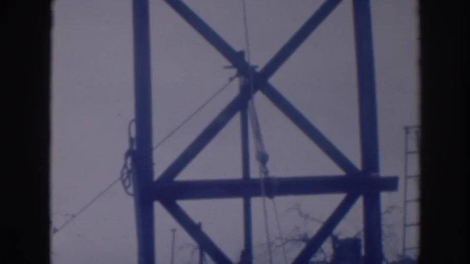 1937 Sacramento 8mm frame showing the lower portion of a cross-braced wooden tower with rigging lines and bare tree branches.