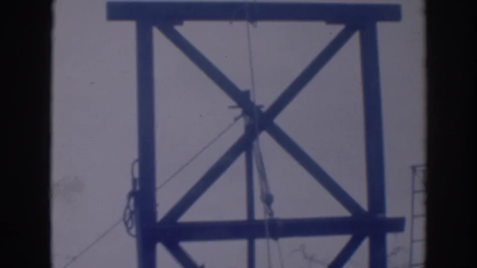 1937 Sacramento 8mm frame showing X-braced wooden tower timbers, a hanging rope line, and a ladder near the right side.