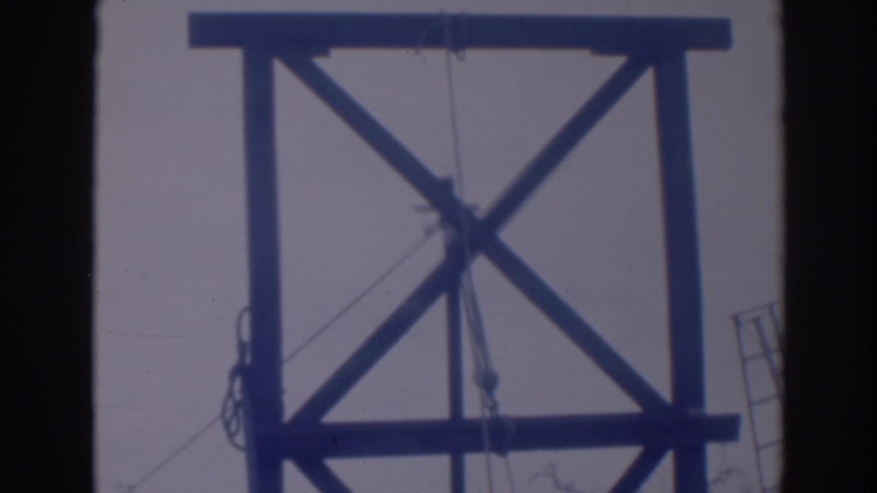1937 Sacramento home-movie frame showing a wooden tower structure with crossed bracing, ropes, and pulley lines in soft blue-tinted focus.