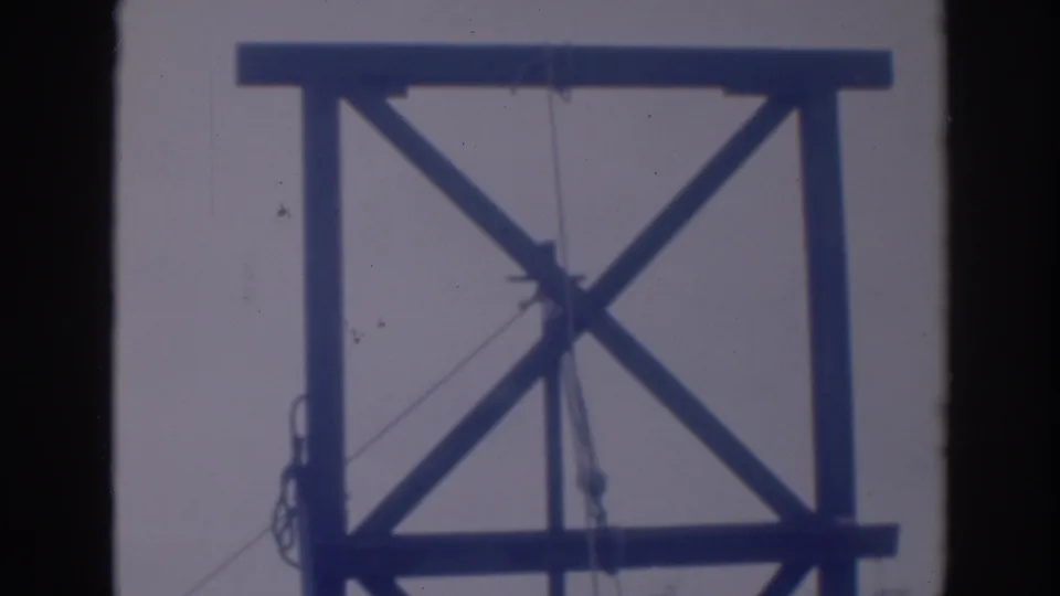 1937 Sacramento footage shows a timber tower frame with diagonal bracing, suspended rigging, and a ladder partly visible along the right edge.