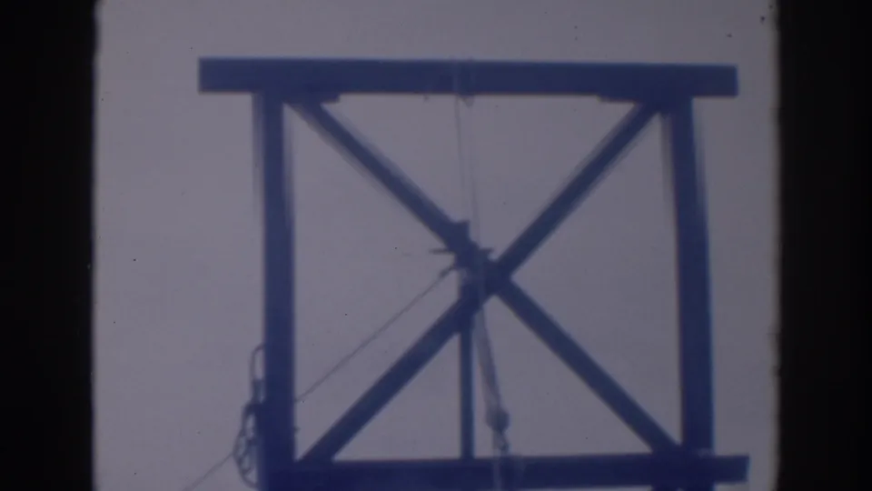 Soft 8mm frame from Sacramento in 1937 showing a tall wooden structure with crossed braces and hanging rope or pulley lines.