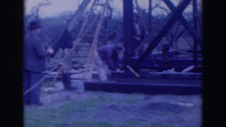 1937 Sacramento construction scene with visible workers handling ropes beside a wooden frame, ladder, and rigging equipment.
