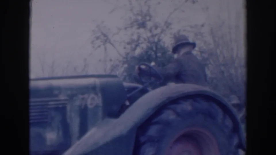 Blue-tinted 8mm frame of an older man driving a tractor in a rural Sacramento setting, dated 1937 in the clip metadata.