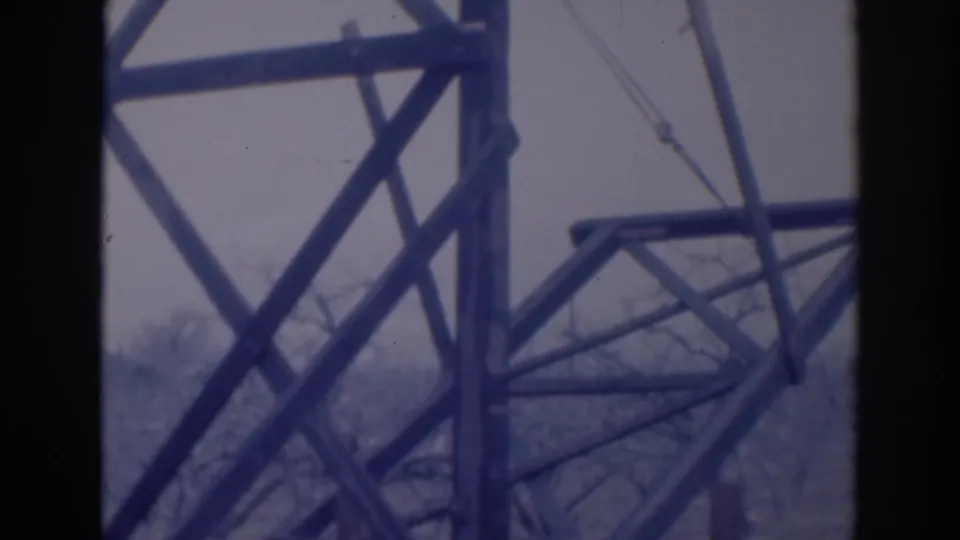 1937 Sacramento frame with intersecting industrial steel members, a horizontal brace, cable lines, and leafless trees behind.
