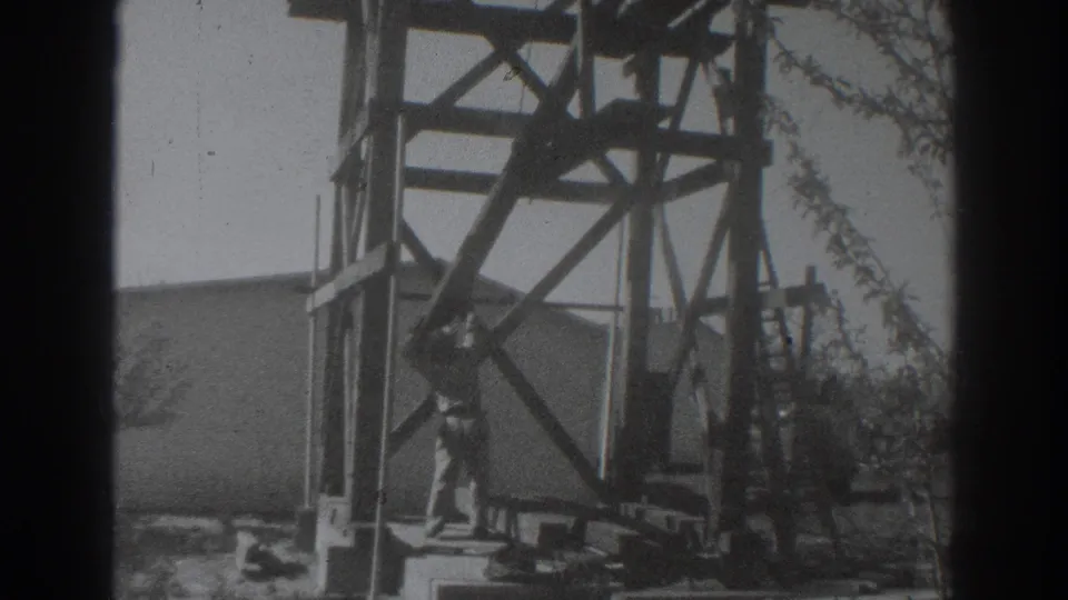 1937 Sacramento home-movie frame showing workers at the base and side of a tall wooden construction frame.