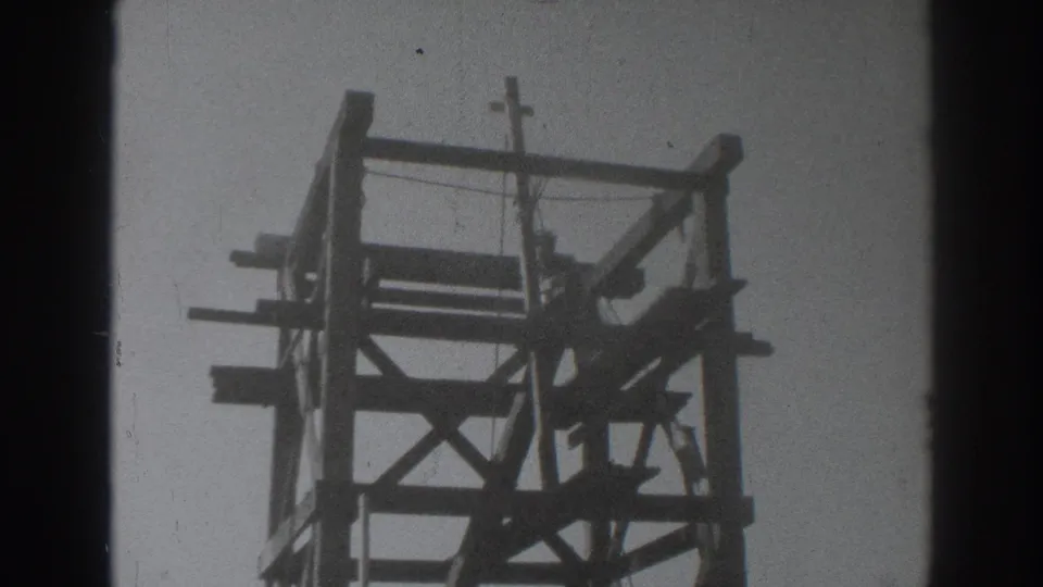 The unfinished wooden tower dominates the frame as a worker appears along the side of the structure in Sacramento, 1937.