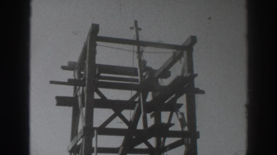 Final frame shows a worker on the Sacramento wooden construction frame, with beams and braces silhouetted against the sky.
