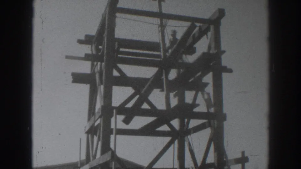 In the 1937 Sacramento home-movie shot, the man appears to guide a board across the top of the wooden tower structure.