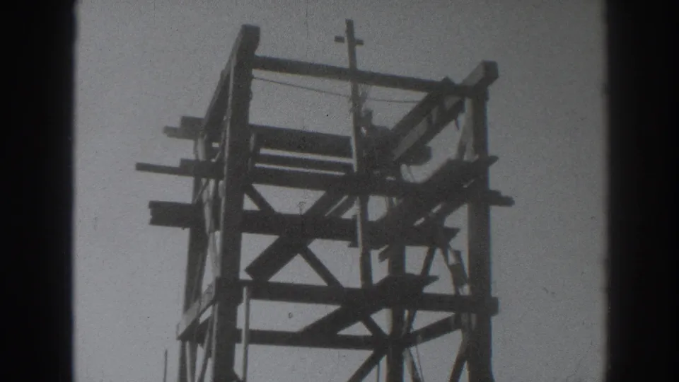 The final frame shows the 1937 Sacramento tower from below, with the worker silhouetted among beams and the crucifix at the top.