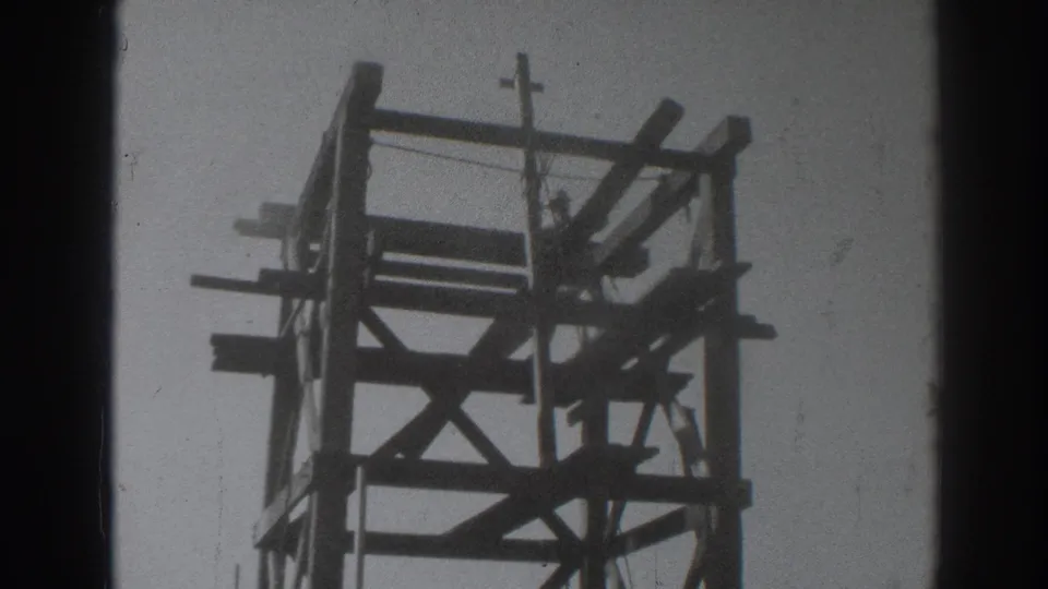 1937 Sacramento 8mm frame showing a worker silhouetted inside a wooden tower framework against the sky.