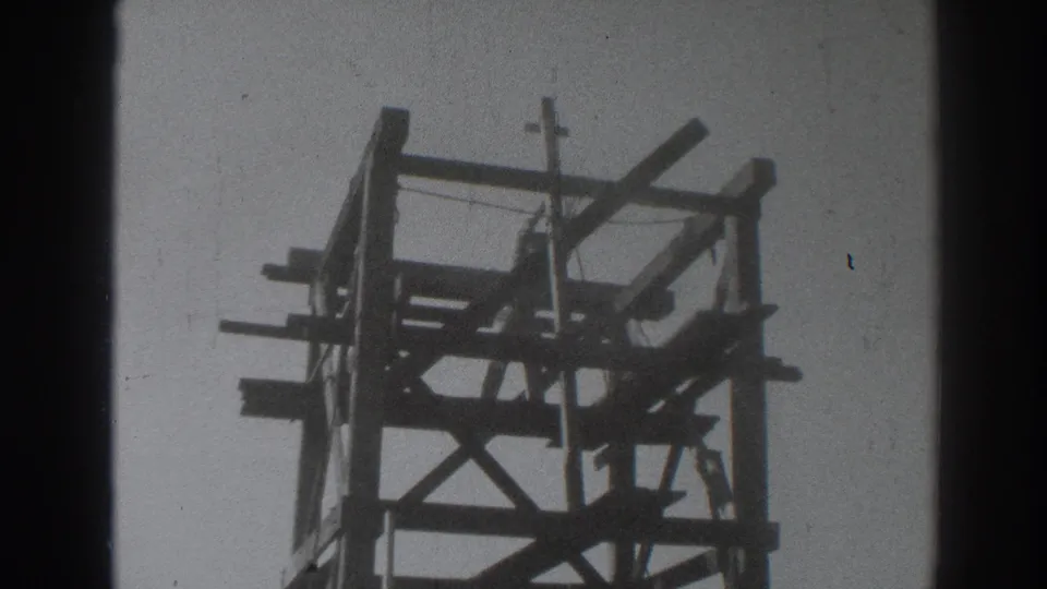 1937 Sacramento 8mm still showing a worker partly hidden among the beams of a timber tower under construction.