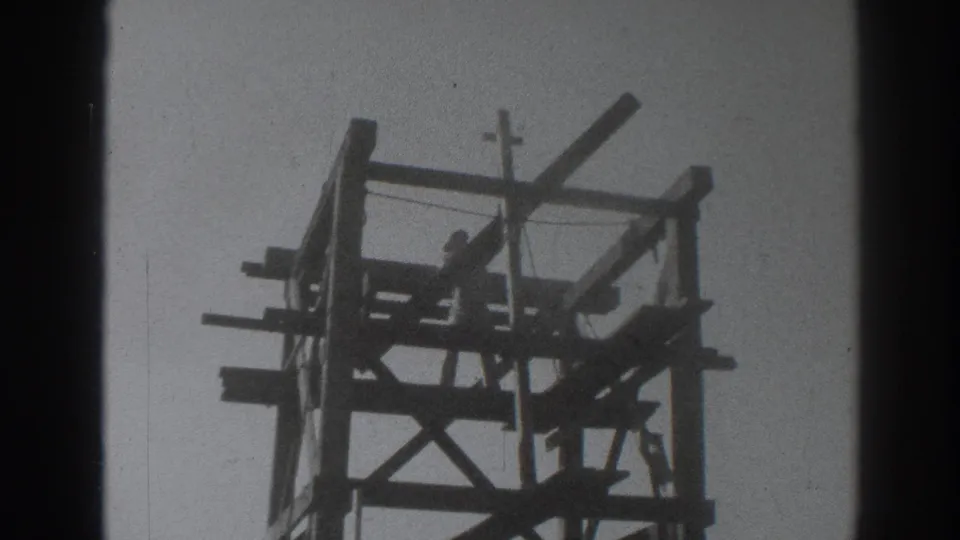 1937 Sacramento frame showing a silhouetted worker near the top of a wooden tower, appearing to handle a beam.