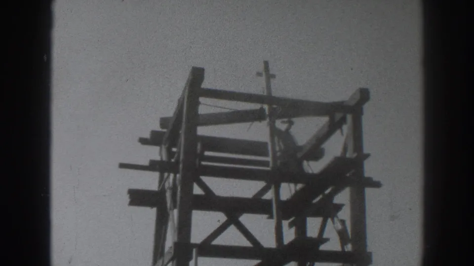 Sacramento 1937 home-movie still with a worker standing inside a timber framework beneath a small crucifix.
