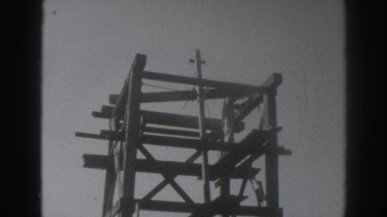 Tall wooden rig frame seen from below against a bright sky.
