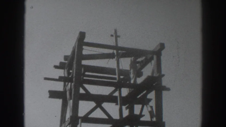1937 Sacramento 8mm frame showing a tall timber oil-rig structure with cross-bracing and a small cross-shaped top element.
