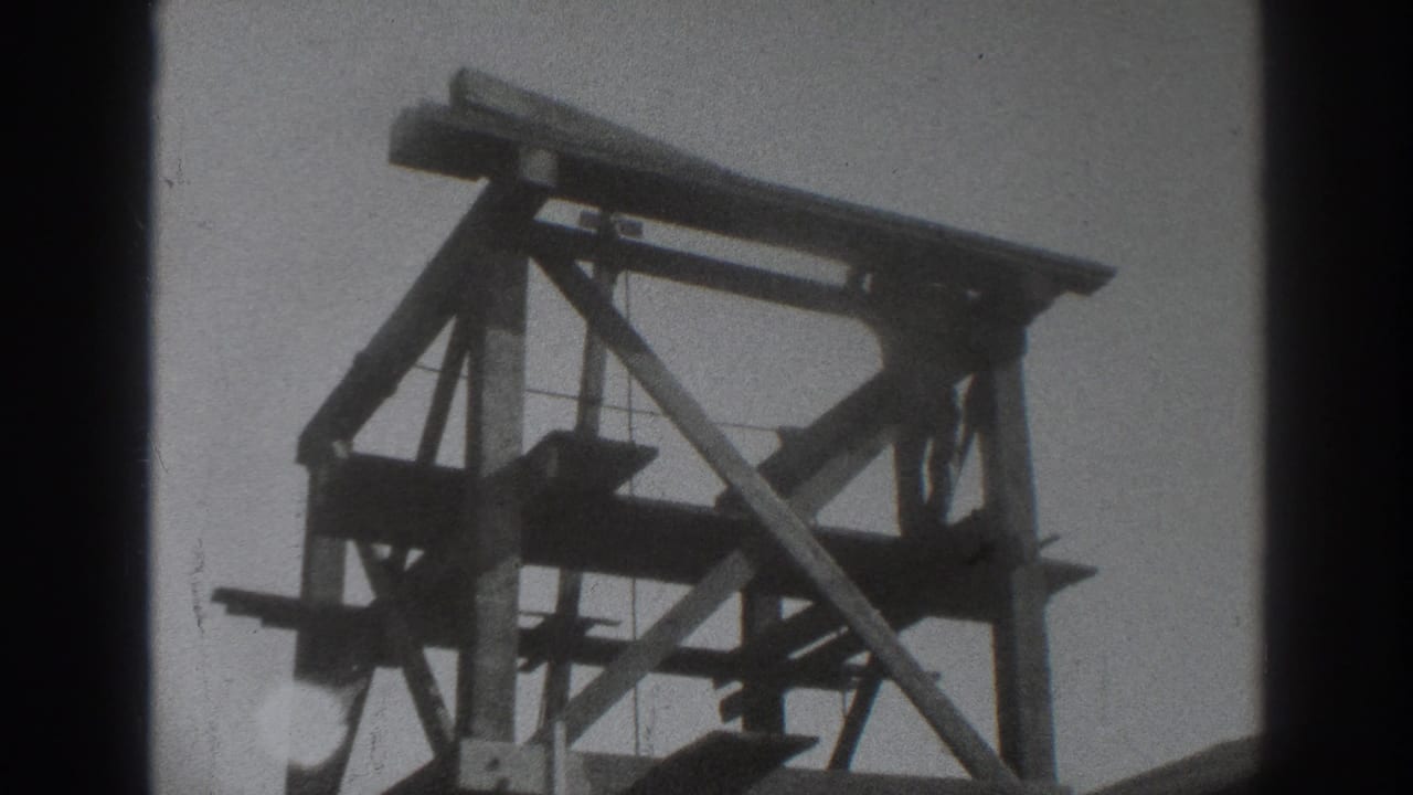Wooden scaffold structure silhouetted against a pale sky.