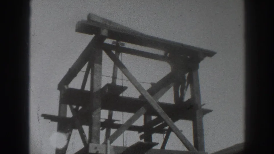1937 Sacramento construction view showing timber scaffolding and braces against a pale sky on grainy 8mm film.