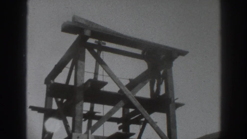 Grainy 8mm frame of a Sacramento construction scaffold in 1937, with a small figure partly visible near the upper structure.