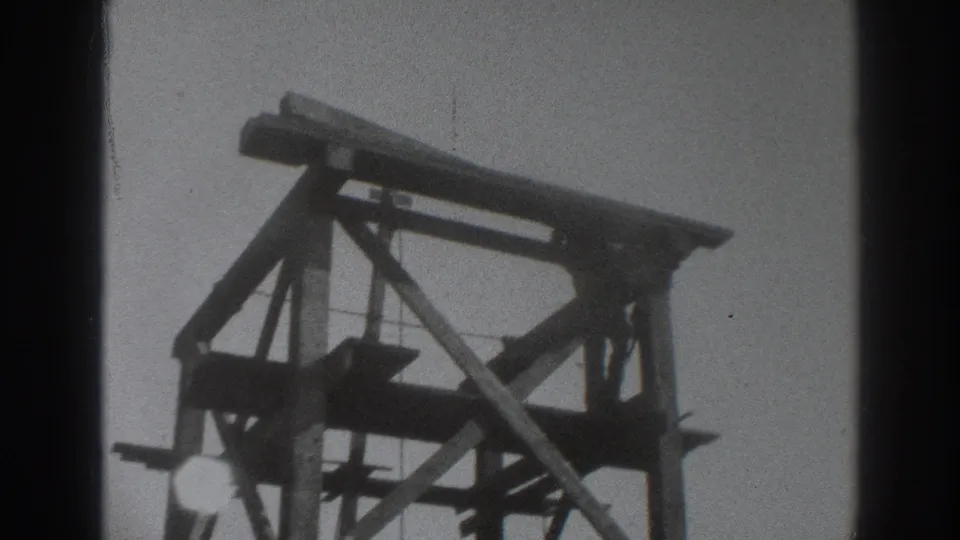 Low-angle 1937 Sacramento construction shot showing timber scaffold beams, diagonal bracing, and visible 8mm grain.
