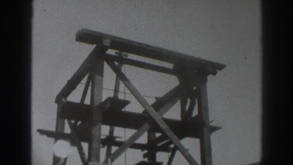 1937 Sacramento home-movie frame showing a wooden scaffold tower and a small worker figure within the upper framing.