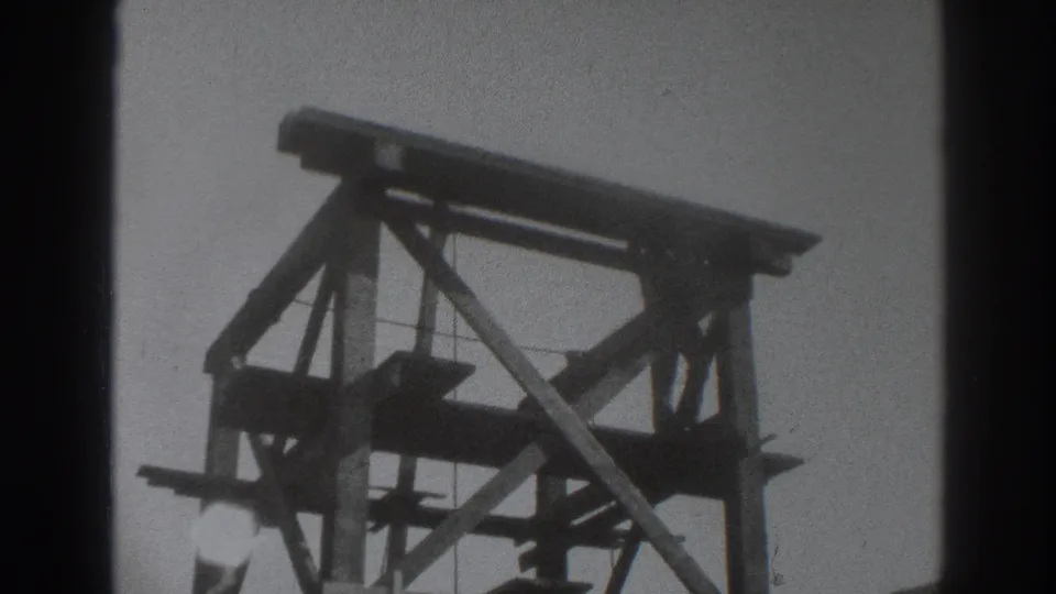 1937 Sacramento 8mm frame showing a tall timber scaffold from below, with diagonal bracing silhouetted against a pale sky.