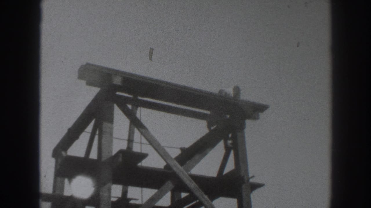 Wooden scaffolding silhouetted against sky with film edge shadows.