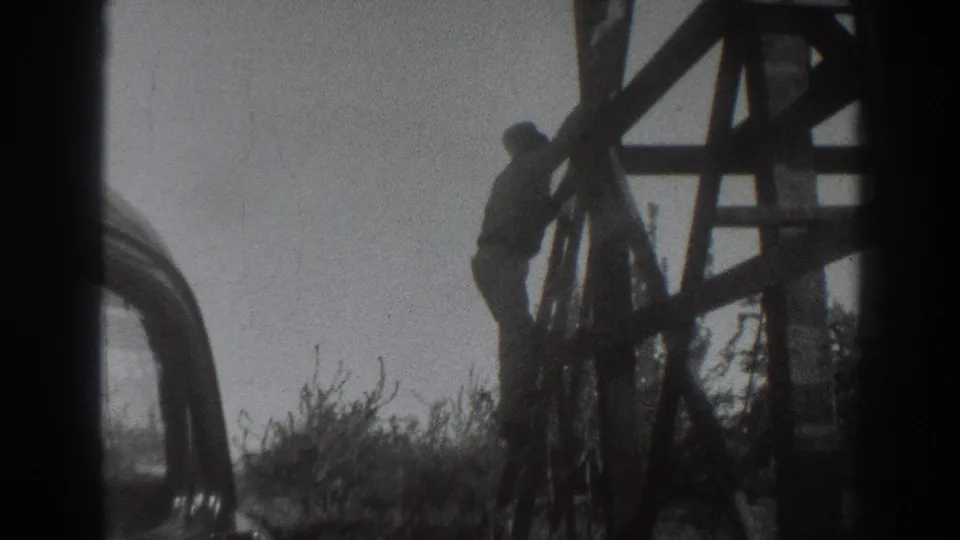 In 1937 Sacramento home-movie footage, a man appears to climb down a tall wooden structure beside an old car and brush.