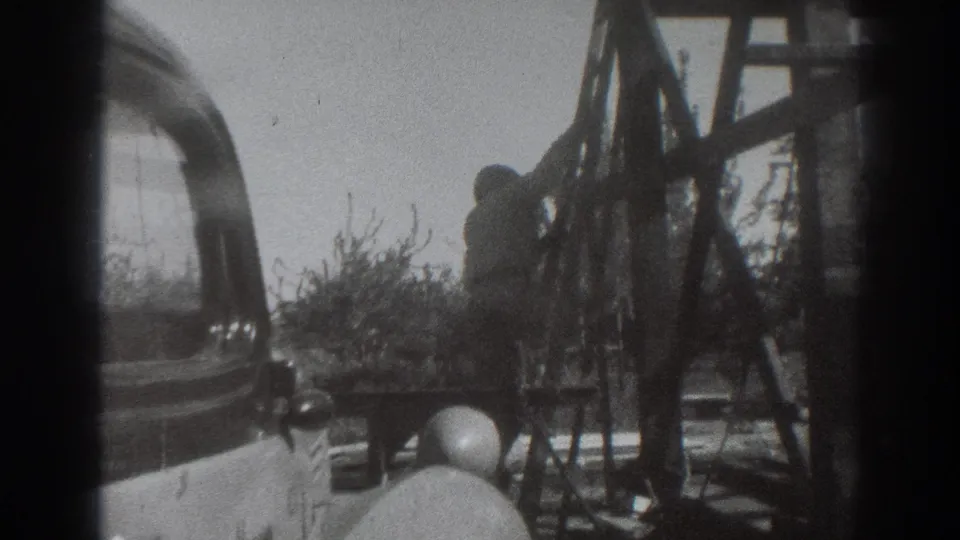 A lower view shows the man descending near the wooden supports, with the old car more visible in the foreground.