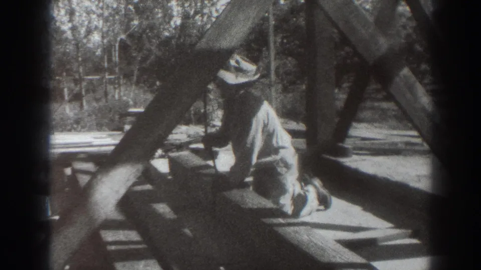Near the end of the clip, the worker kneels upright beside rope and heavy beams in the outdoor Sacramento construction scene.