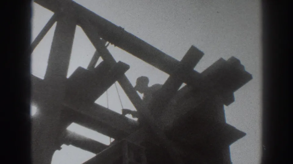 In Sacramento home-movie footage from 1937, a worker is silhouetted within an unfinished wooden house frame.