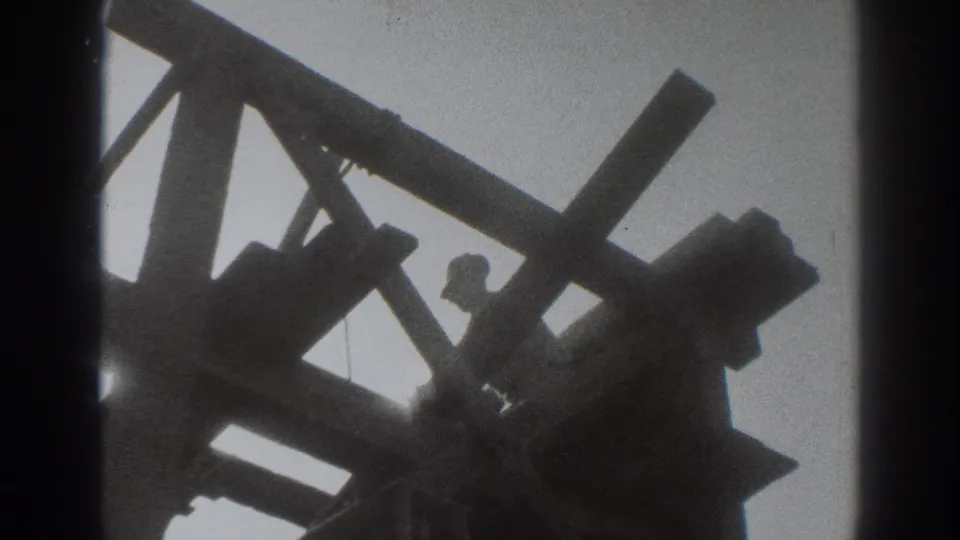 A silhouetted worker stands within the Sacramento wooden framing, partly obscured by beams and rafters.