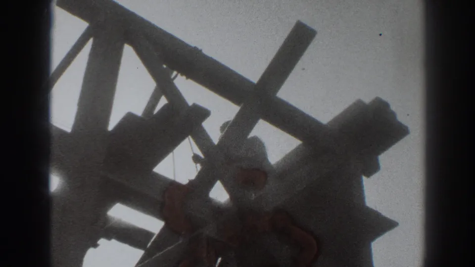 A worker bends near the unfinished wooden frame, with the 1937 Sacramento scene softened by 8mm exposure and grain.