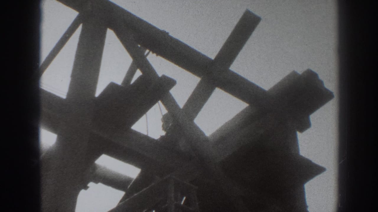 Low-angle view of timber framing with a worker partly visible against a bright sky.