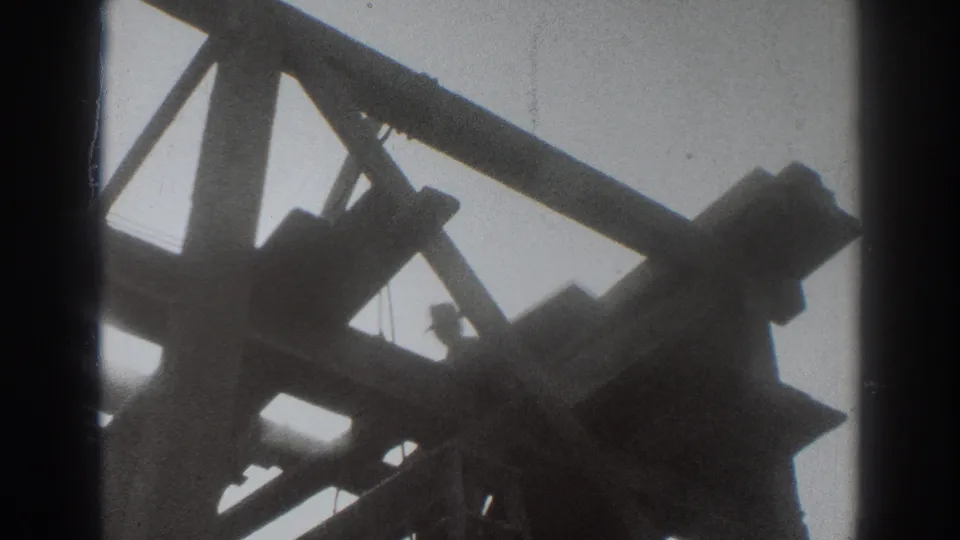 1937 8mm construction view with a worker partly obscured by Sacramento timber framing and diagonal beams.