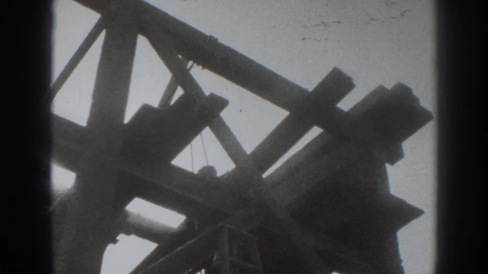 Low-angle 1937 Sacramento view of dark timber truss work with a small hanging element near the center.