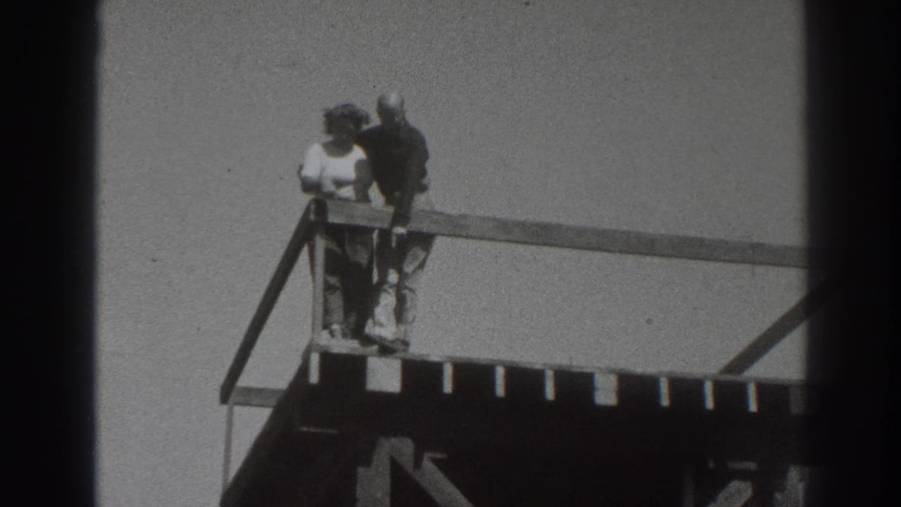 In 1937 Sacramento footage, a couple stands near the corner of a wooden platform, looking outward from an elevated railing.