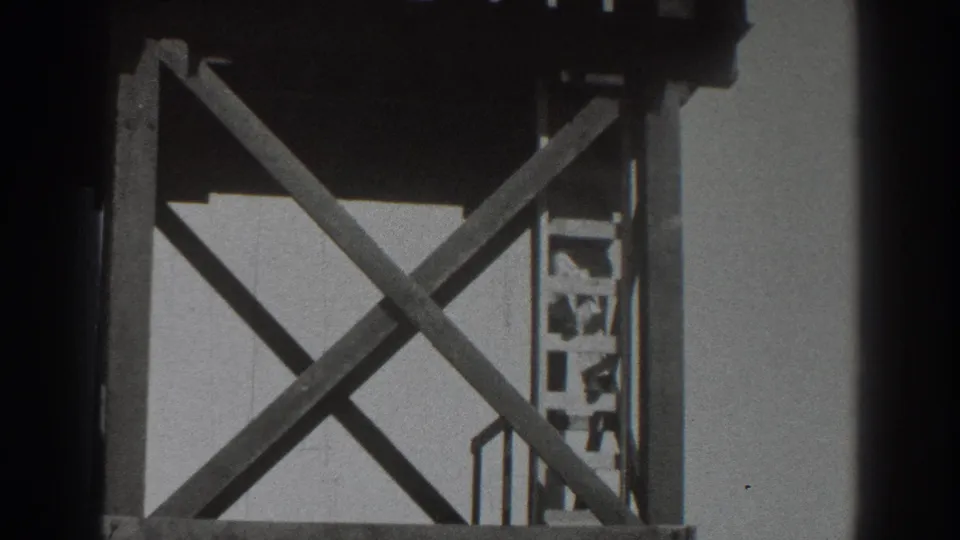 A 1937 Sacramento construction view shows a man partly obscured near the platform edge of a wooden scaffold with diagonal bracing.