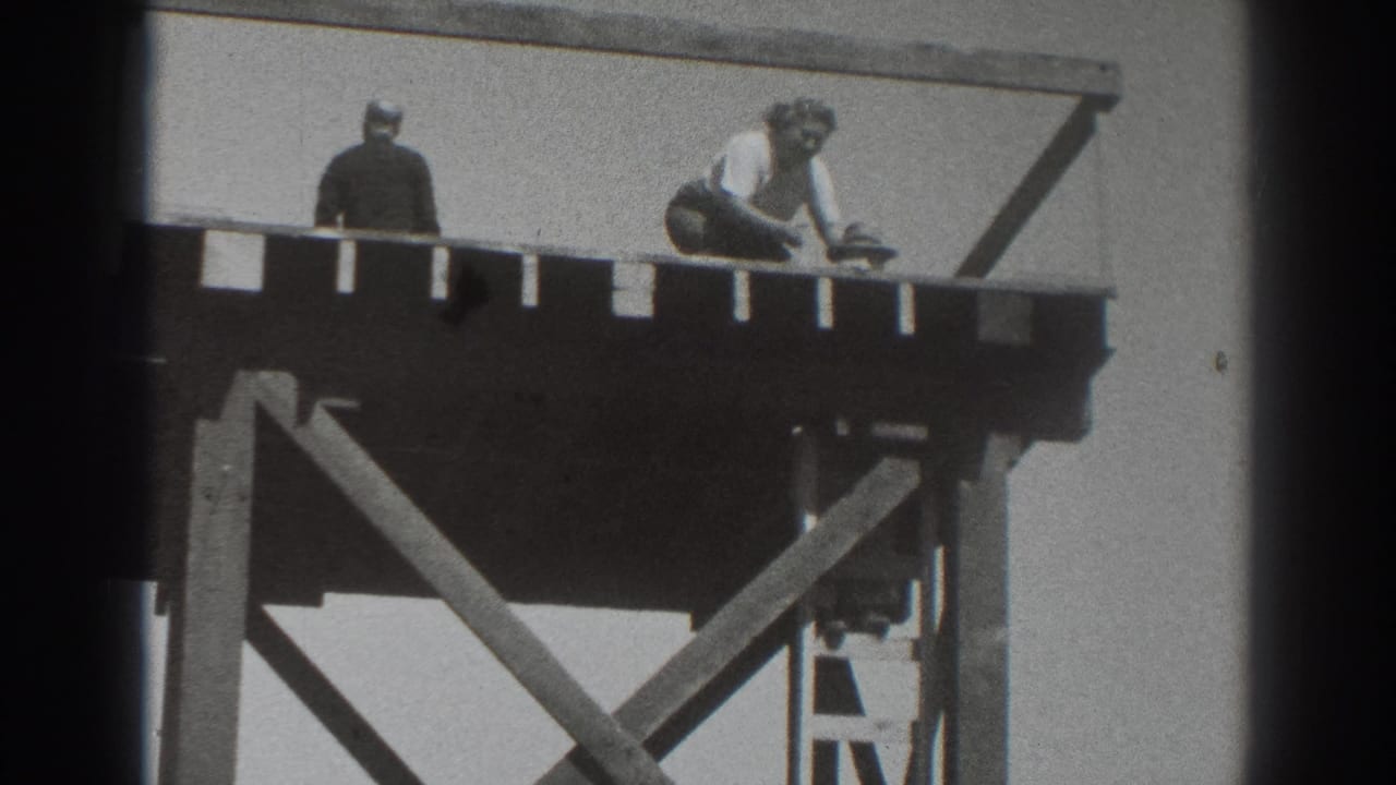 A person crouches on the platform near another standing figure.
