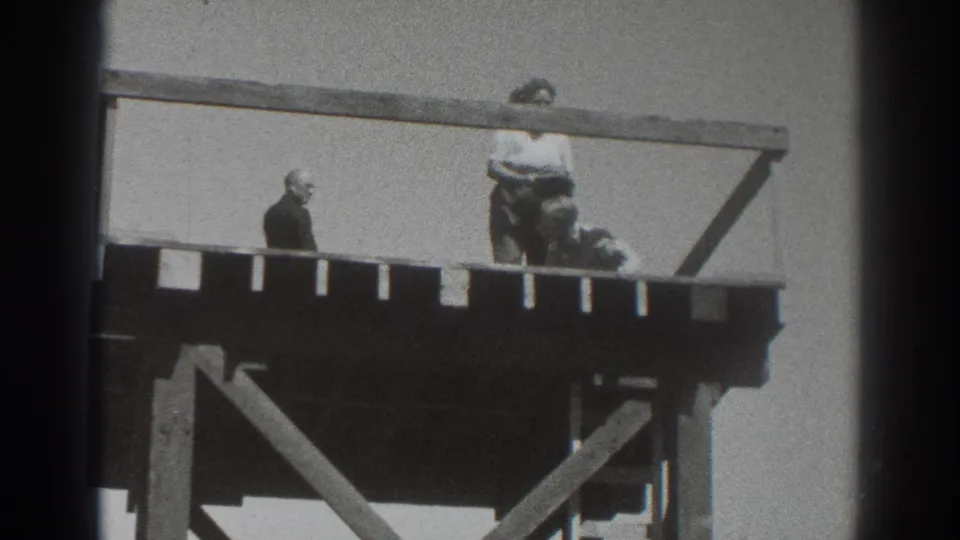 1937 Sacramento home-movie frame showing two people on a raised wooden platform with open railings against a bright sky.