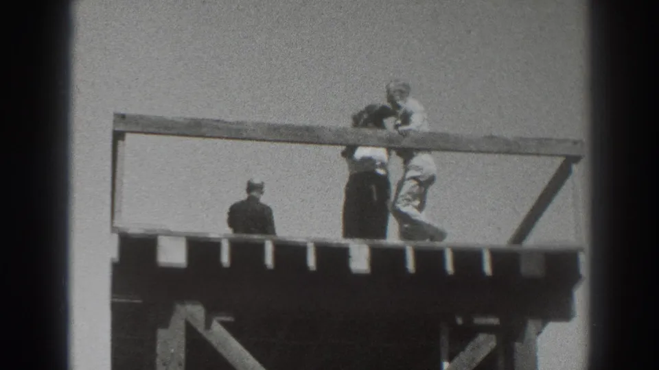 1937 Sacramento footage frame showing people close together at the rail of an elevated wooden platform, with one figure facing away.