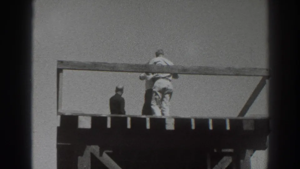 1937 Sacramento home-movie frame showing figures on a raised wooden tower deck, with one person at the rail and another turned away.