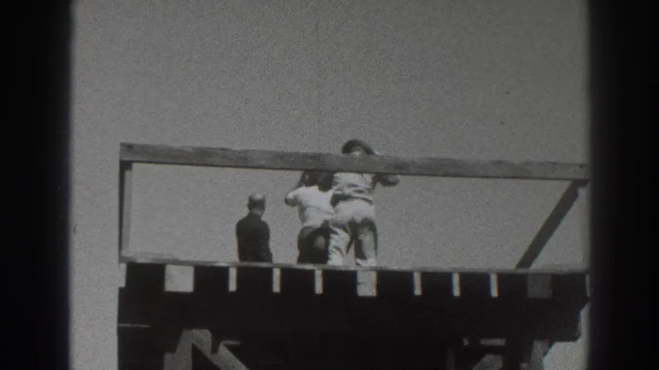 1937 Sacramento home-movie frame showing three adults on a raised wooden deck, with one dark-suited figure and two lighter-clothed figures near the railing.