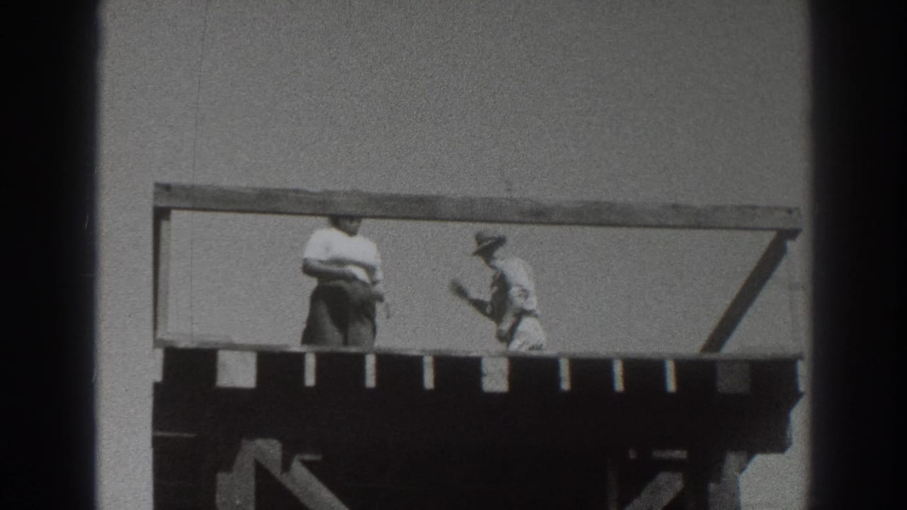 1937 Sacramento frame showing two adults on a raised wooden deck, one near the center and one in a hat by the railing.