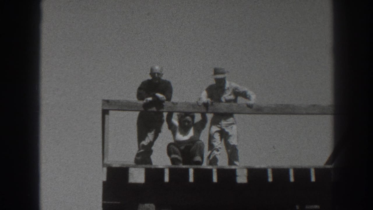 Adults on the upper level of a wooden tower, with one person crouched below the railing and two others standing nearby.