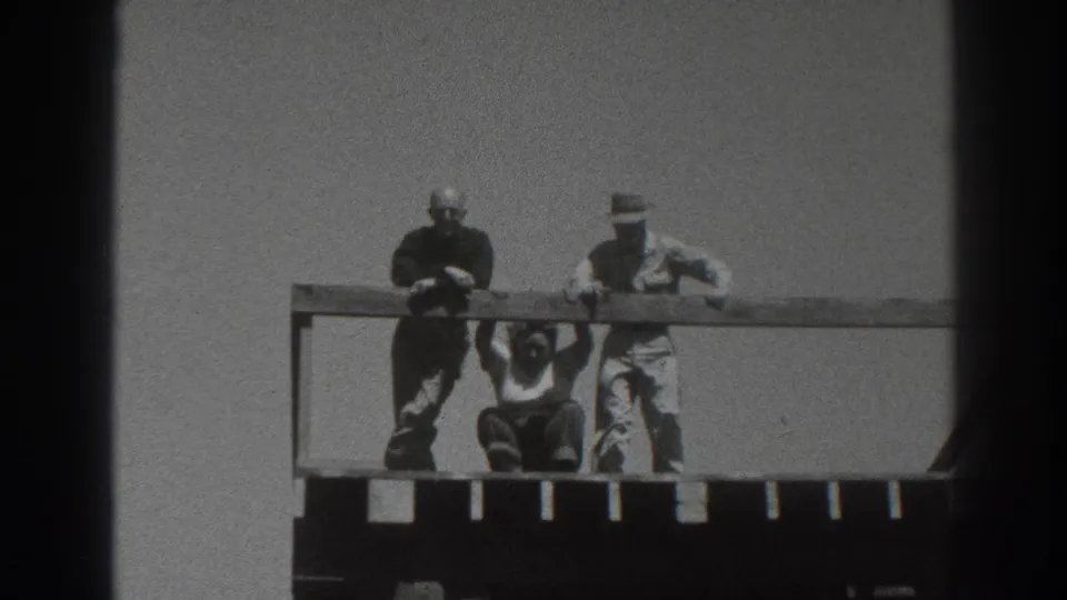 Adults on the upper level of a wooden tower, with one person crouched below the railing and two others standing nearby.