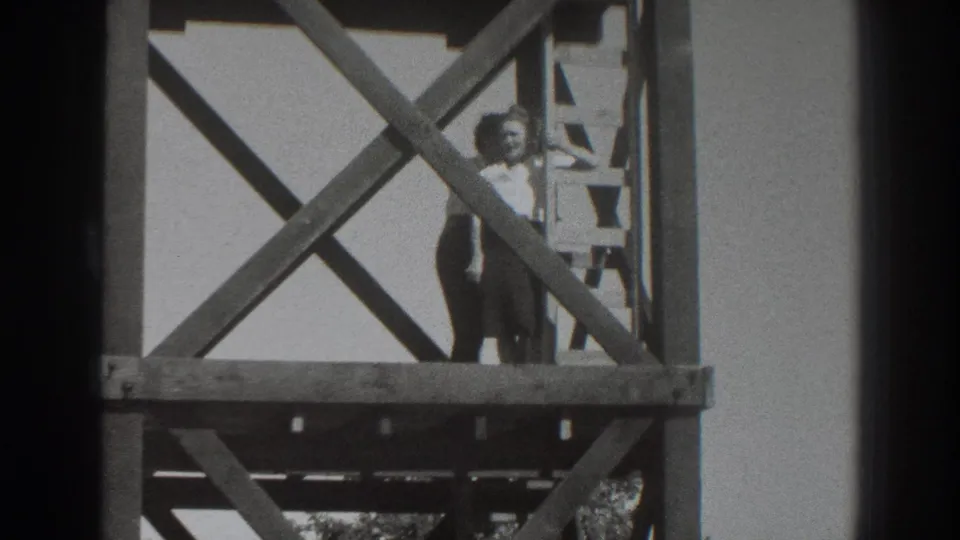 In 1937 Sacramento home-movie footage, a woman stands on a raised wooden scaffold as a man climbs beside her.