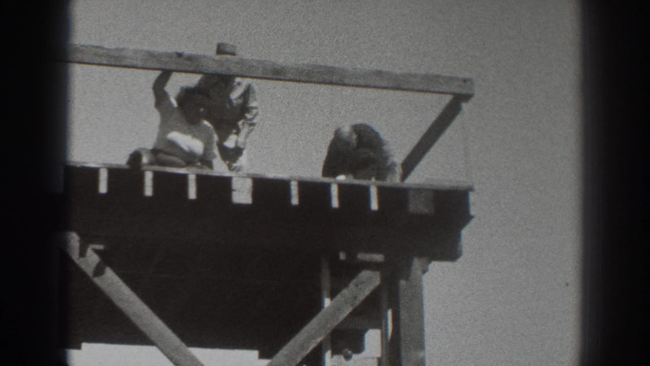 1937 Sacramento frame showing three men clustered on an elevated wooden platform, with one near the rail, one bending, and the tower braces below.