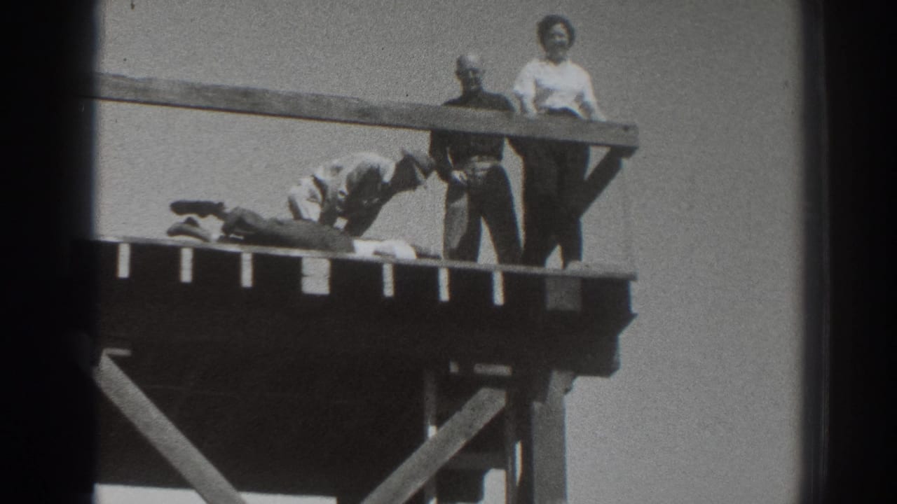 1937 Sacramento footage shows a woman in a light blouse and two men near a prone person on a high wooden platform.